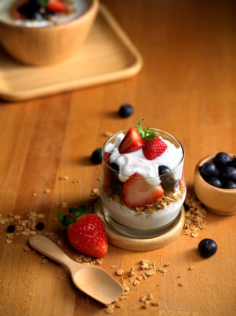 Bicchiere di muesli con yogurt greco naturale e frutti di bosco freschi sul tavolo di legno