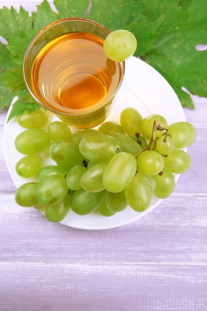 Glass of grape juice on wooden table, closeup