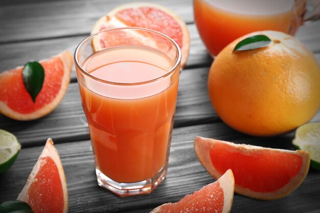 Glass of grapefruit juice and fresh fruits on wooden background