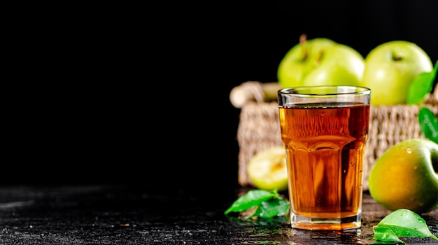 A glass of green apple juice with leaves on the table