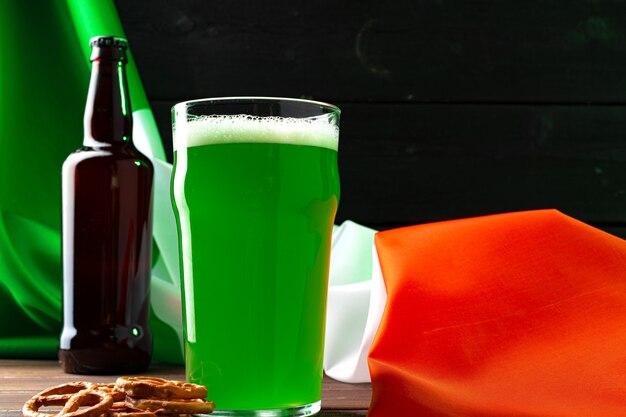 Glass of green beer against flag of Ireland close up