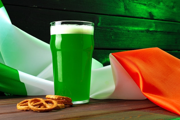 Glass of green beer against flag of Ireland close up