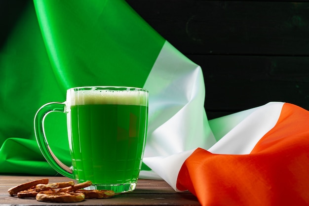 Glass of green beer against flag of Ireland close up