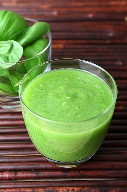 Glass of green healthy juice with spinach and basil on table close up