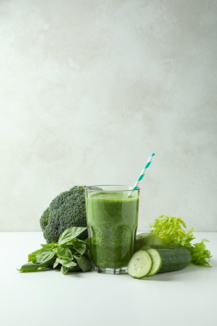 Photo glass of green smoothie and ingredients on white table