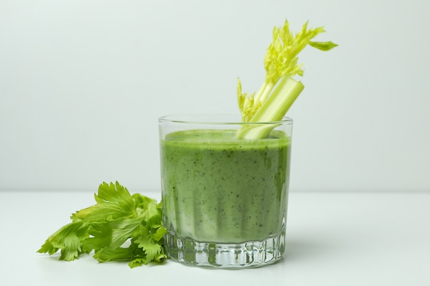 Glass of green smoothie with Ñelery on white table