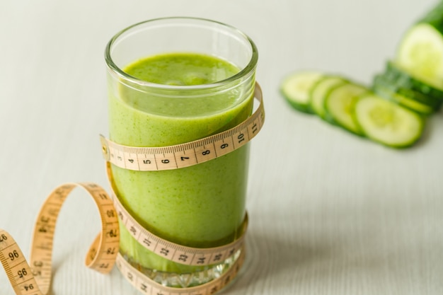 A glass of green vegetable smoothies on a white wooden background