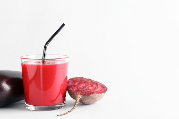 Glass of healthy smoothie with beet and eggplant on white surface