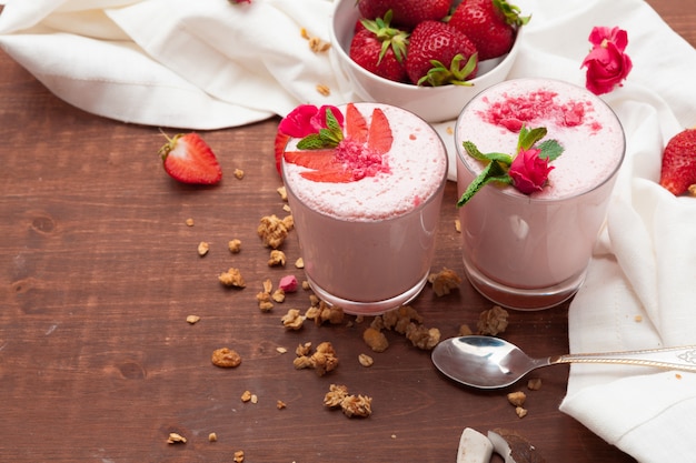 Glass of healthy strawberry yogurt with fresh berries on wooden surface table top view