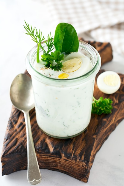 Glass of healthy yogurt with a variety of herbs, spinach, dill, onions, parsley and quail eggs. The concept of a vegetarian breakfast. Selective focus.