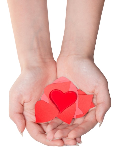 Glass heart above pile of hearts on female palms