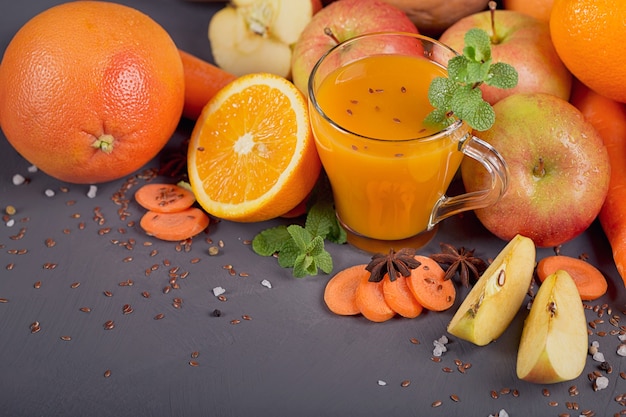 Glass of homemade juice or smoothie, fruits and vegetables. Fresh carrot, apple, pumpkin, orange, grapefruit on dark table. Healthy eating, food, dieting, detox and vegetarian concept.