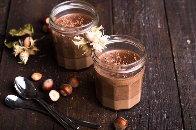 Glass of homemade yogurt with chocolate mousse and chocolate candy and spoon