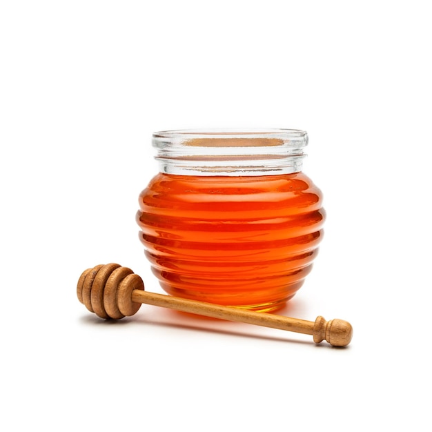 Glass of honey in a jar with a wooden honey dipper, isolated on white background