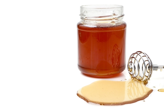 A glass of honey with dipper on a white background. copy space