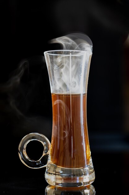 Photo glass of hot coffee steam swirling against a dark background