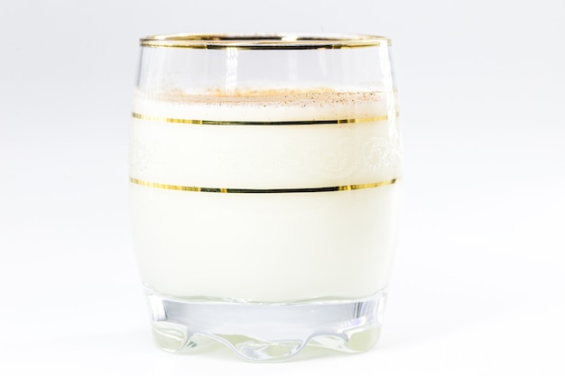 Glass of hot eggnog, Christmas drink, made with eggs, cinnamon, almonds and rum liqueur. Isolated white background and copy space.