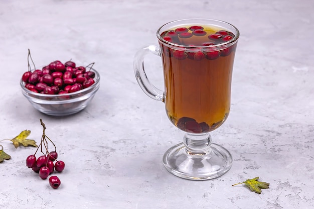 A glass of hot hawthorn berry tea on a concrete background