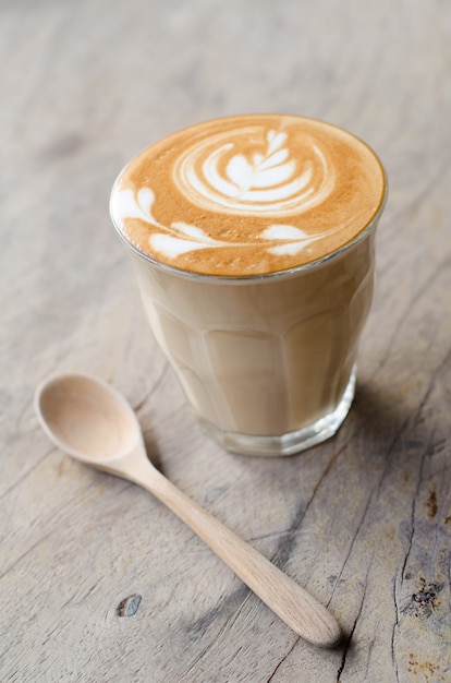 a glass of hot latte art coffee on wooden table 