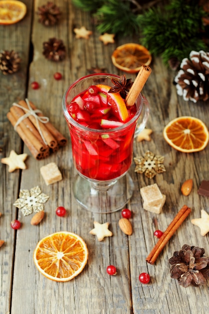 Glass of hot mulled wine for the new year with ingredients for cooking, nuts and christmas decorations