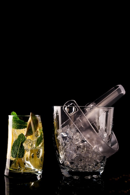 Glass ice bucket and mohito cocktail in glass isolated on black