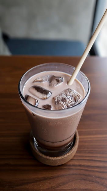 A glass of ice chocolate milk at a table with a straw