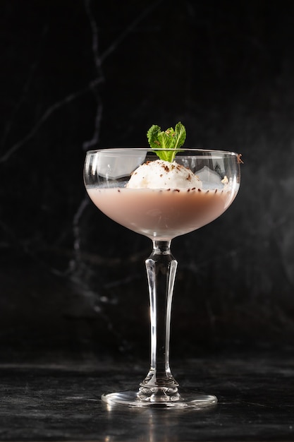 Glass of ice cold Baileys cocktail served in a coupe glass decorated with mint leaf placed