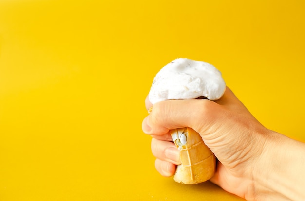 A glass of ice cream melts in the hand on a yellow .