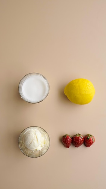 A glass of ice cream with strawberries and lemons on a beige background