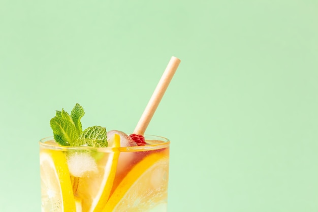 Photo glass of ice tea with lemon and mint leaves on a mint background