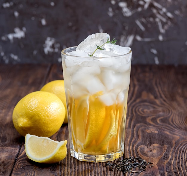Glass of ice tea with lemon on wooden table