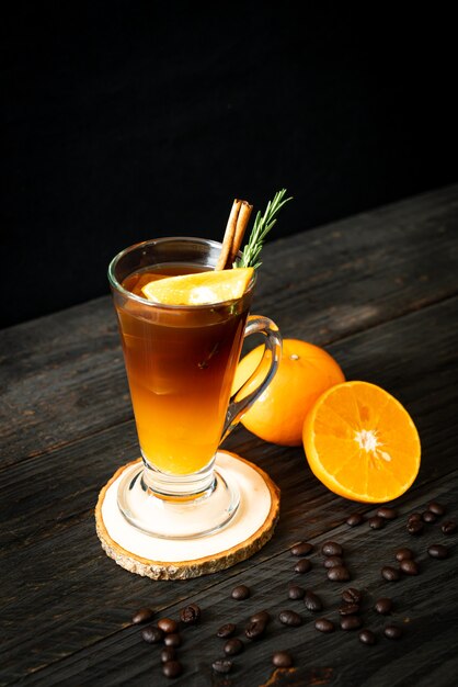 Стакан черного кофе американо со льдом и слой апельсинового и лимонного сока, украшенный розмарином и корицей
