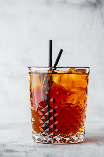 Glass of iced black tea with lemon isolated on bright marble background. Overhead view, copy space. Advertising for cafe menu. Coffee shop menu. Vertical photo.