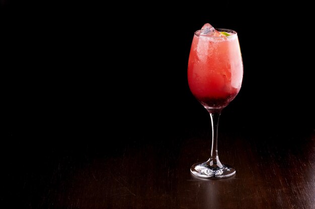 glass of iced cocktail with red campari fruits isolated on dark background