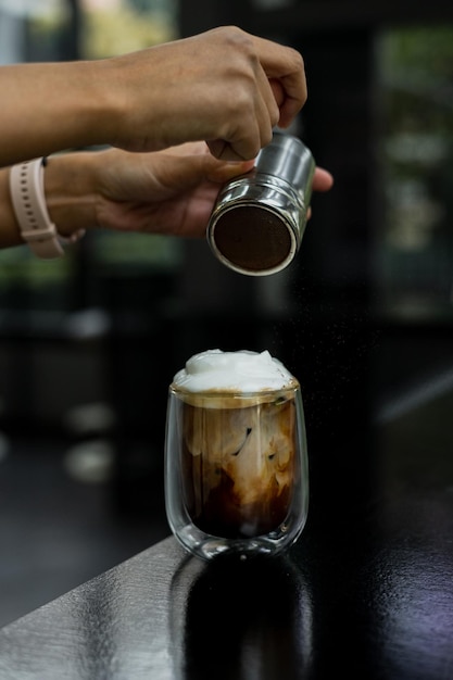 A glass of iced coffee is positioned on the countertop of a bar
