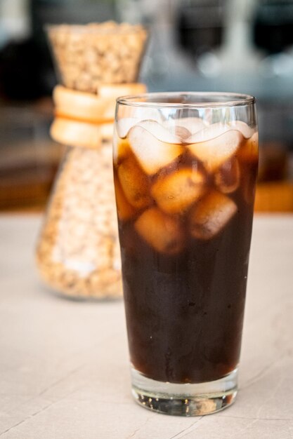 Foto un bicchiere di caffè ghiacciato si trova su un tavolo con un barattolo di caffè dietro.