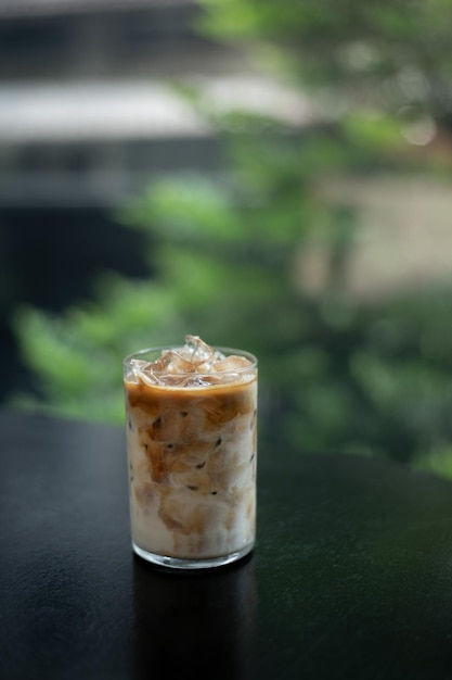 A glass of iced coffee with a green background