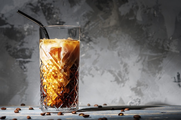 A glass of iced coffee with milk against a concrete wall with copies of the space.