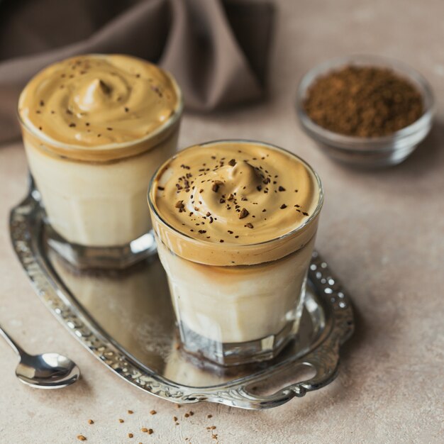 Glass of Iced Dalgona Coffee, a trendy fluffy creamy whipped coffee and milk on light beige