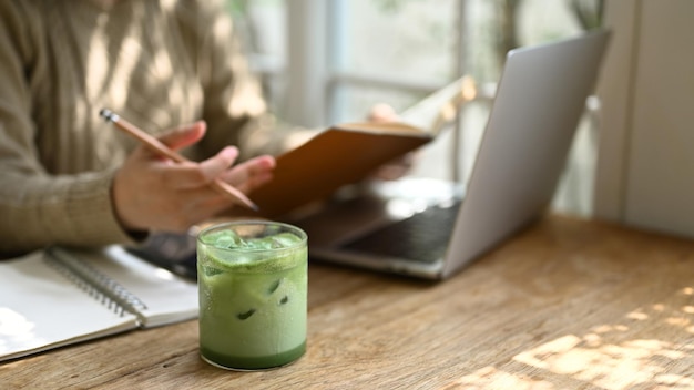 A glass of iced matcha green tea on a wooden table in a minimal cafe