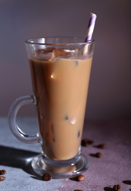 Glass of iced milk coffee on color wooden table on dark background