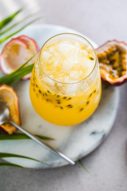 Glass of Iced passion fruit soda with lemon and passion fruit half slice on a light background refreshing drink or beverage with ice