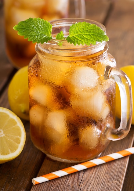 Glass of iced tea with fresh lemons on wooden table