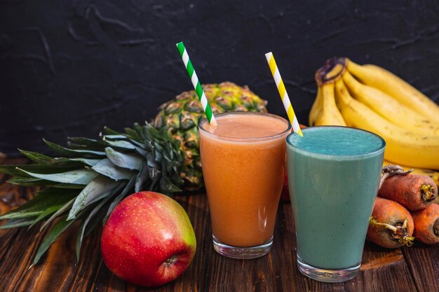 Glass is filled with fresh and useful smoothie made from spicy juicy vegetables and fruits Drink is sitting on a wooden table near the ingredients from which it is cooked illuminated by warm daylight