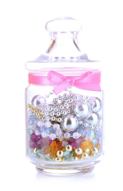 Glass jar containing various beads isolated on white