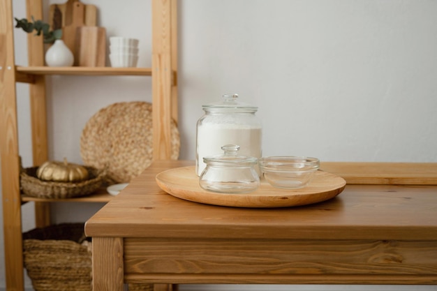 A glass jar of flour on a wooden table in the kitchen