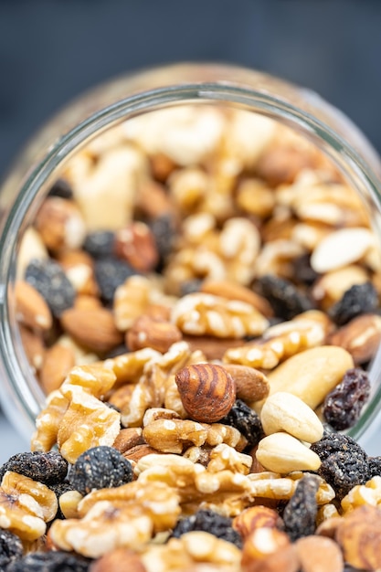 Glass jar full of assorted nuts with almonds hazelnuts cashews and raisins in a macro photograph shot