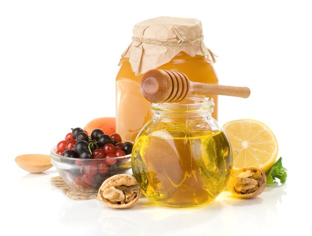 Glass jar full of honey, lemon and berry isolated on white