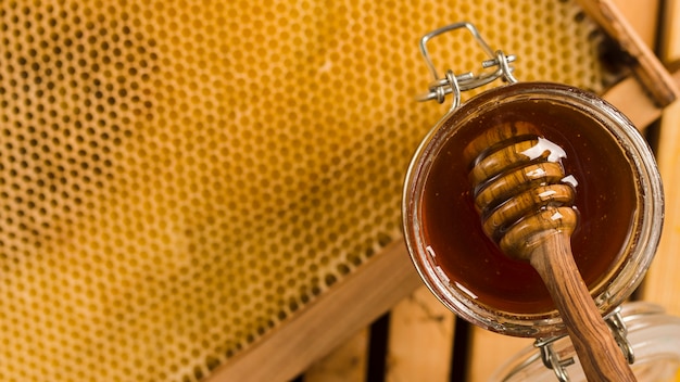 Glass jar full of honey with honey spoon