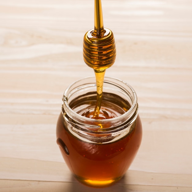 Glass jar full of honey with honey spoon